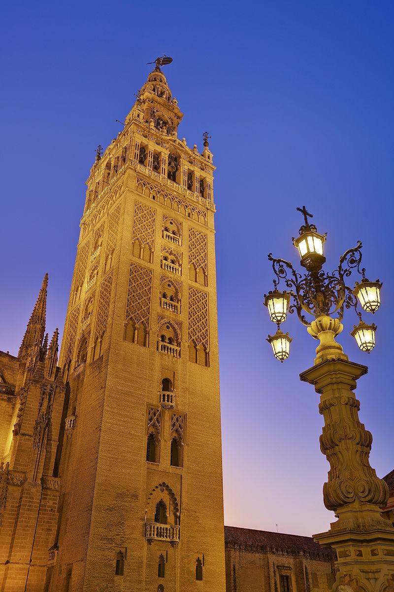 De toren van de kathedraal van Sevilla (mudejar-stijl), La Giralda, gezien vanaf het Plaza Virgen de los Reyes in Sevilla. De kathedraal is een mix van stijlen waaronder, almohaden , laatgotiek (islamitische architecteur), renaissance en barok.