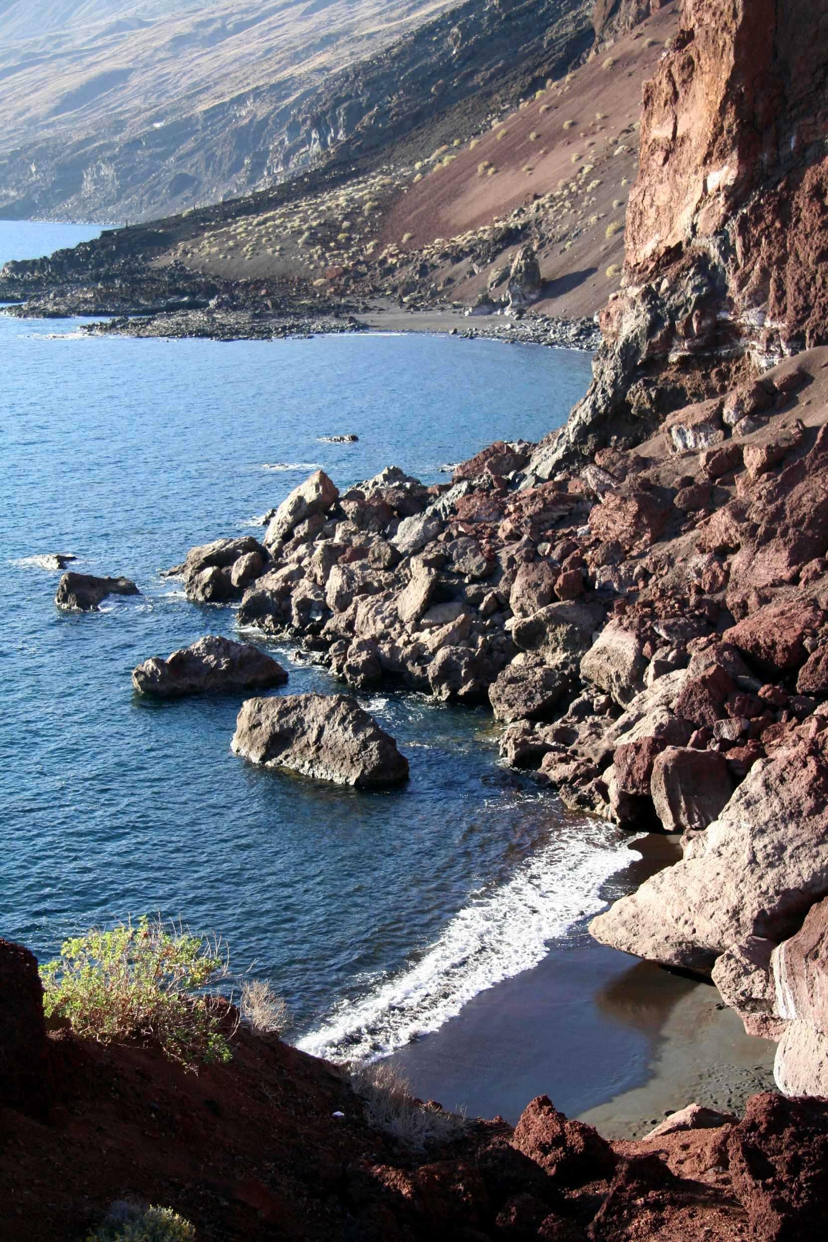 Een stukje van de kustlijn van het eiland waaraan we de vulkanische oorsprong van het eiland goed kunnen zien. Het zwarte strandje rechtsonder en de vele vulkanische rotsblokken.